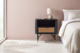 Olbia black acacia and rattan nightstand with a ceramic lamp beside a bed in a Palm Springs bedroom with a dusty blush pink plaster wall and a terrazzo floor