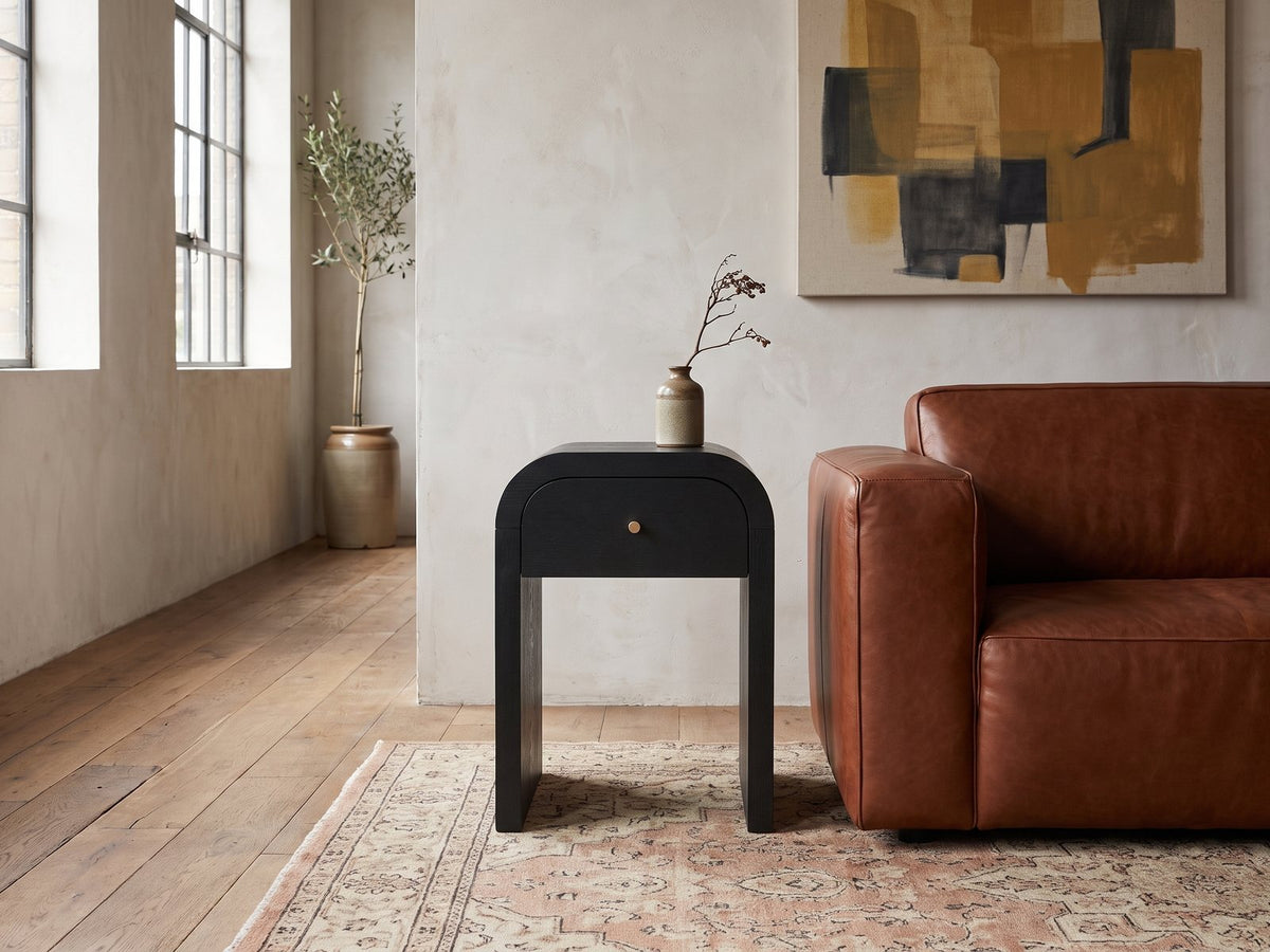 Oppido Black Ash Veneer Waterfall Side Table beside a leather sofa in an industrial loft