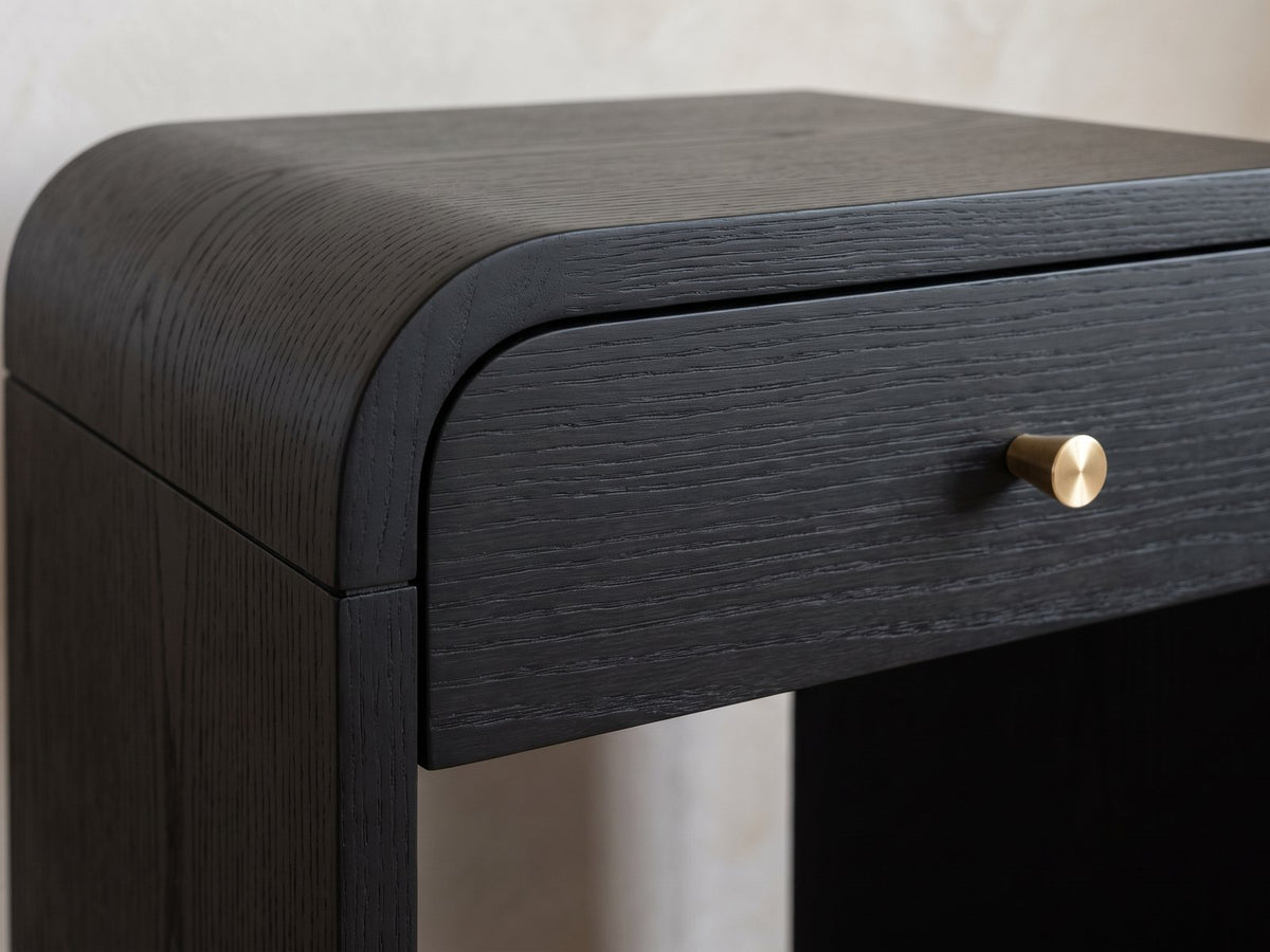 Close-up of the Oppido Black Ash Veneer Waterfall Side Table: the rounded waterfall corner over the drawer and brass knob