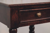 The drawer of the Orani nightstand up close: a flat front in a raised moulding with a round antique brass knob, beneath the softly rounded top