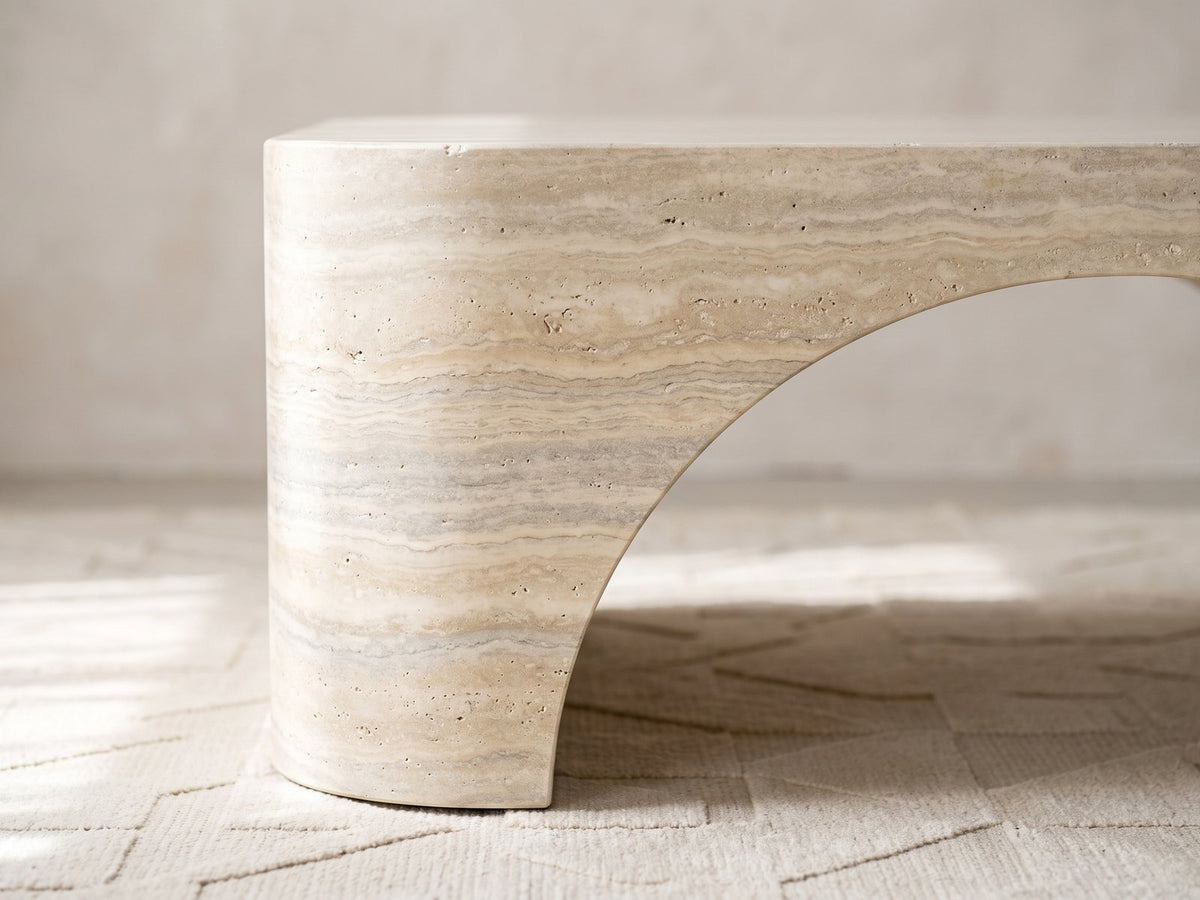 Close-up of the Orbetello Faux Travertine Oval Arch Coffee Table: the arch sweeping up from one end foot into the travertine-look band