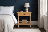 Orgosolo Camel Oak nightstand with a ceramic lamp and a seagrass basket against navy-blue panelled walls in a Boston brownstone bedroom with a dark herringbone floor