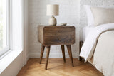 Oristano grey-washed mango nightstand against a whitewashed brick wall in a Brooklyn bedroom with herringbone oak floors
