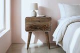 Oristano grey-washed mango nightstand against a soft blush pink plaster wall in a Palm Springs bedroom with a polished concrete floor