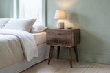 Oristano grey-washed mango nightstand with a ceramic lamp in a Portland bedroom with a soft sage green plaster wall and pale ash floors