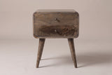 The Oristano two-drawer nightstand in grey-washed mango with bronze-tone knobs, rounded corners and four splayed round legs, straight front view on a light studio backdrop