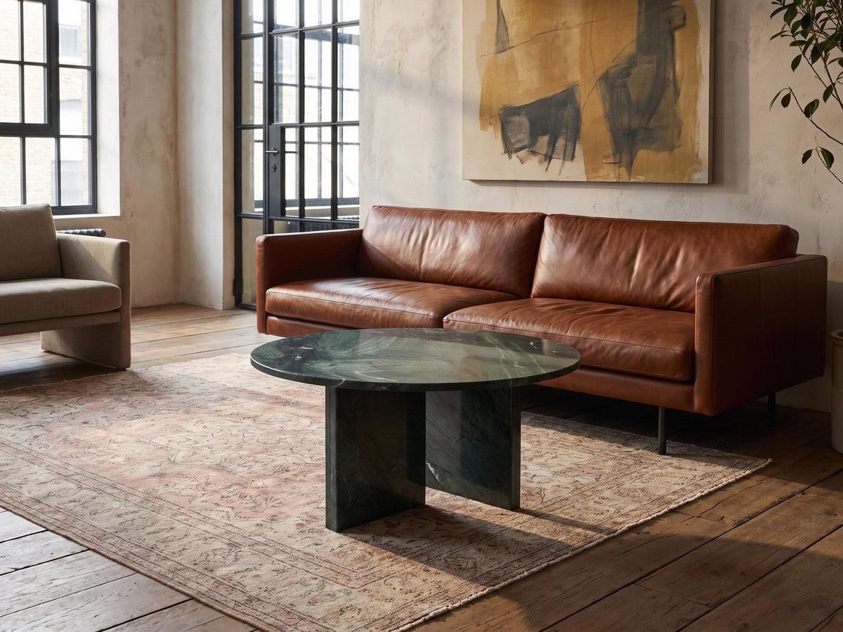 Orosei Verde Marble Coffee Table on a vintage rug in front of a leather sofa in an industrial loft
