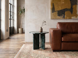 Orosei Verde Marble Round Side Table beside a leather sofa in an industrial loft