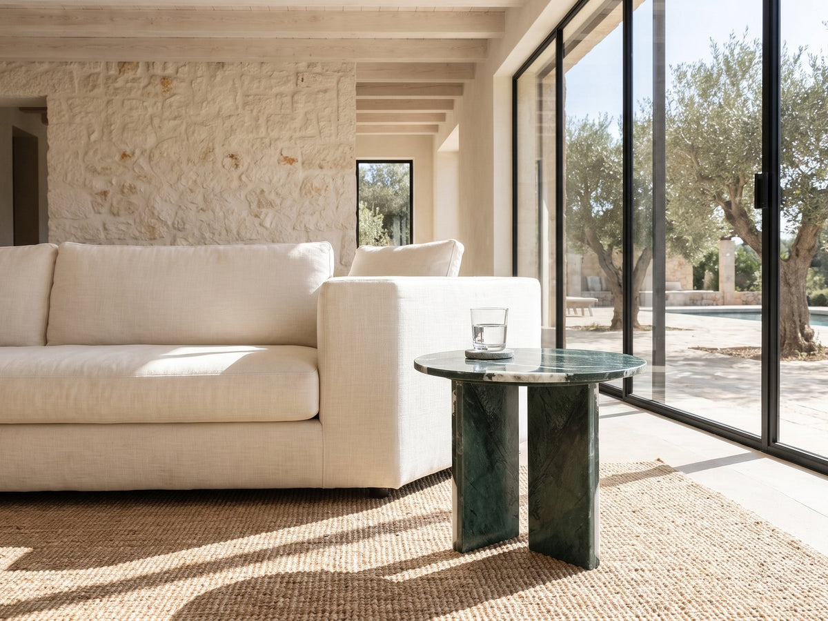 Orosei Verde Marble Round Side Table beside a linen sofa in a poolside villa