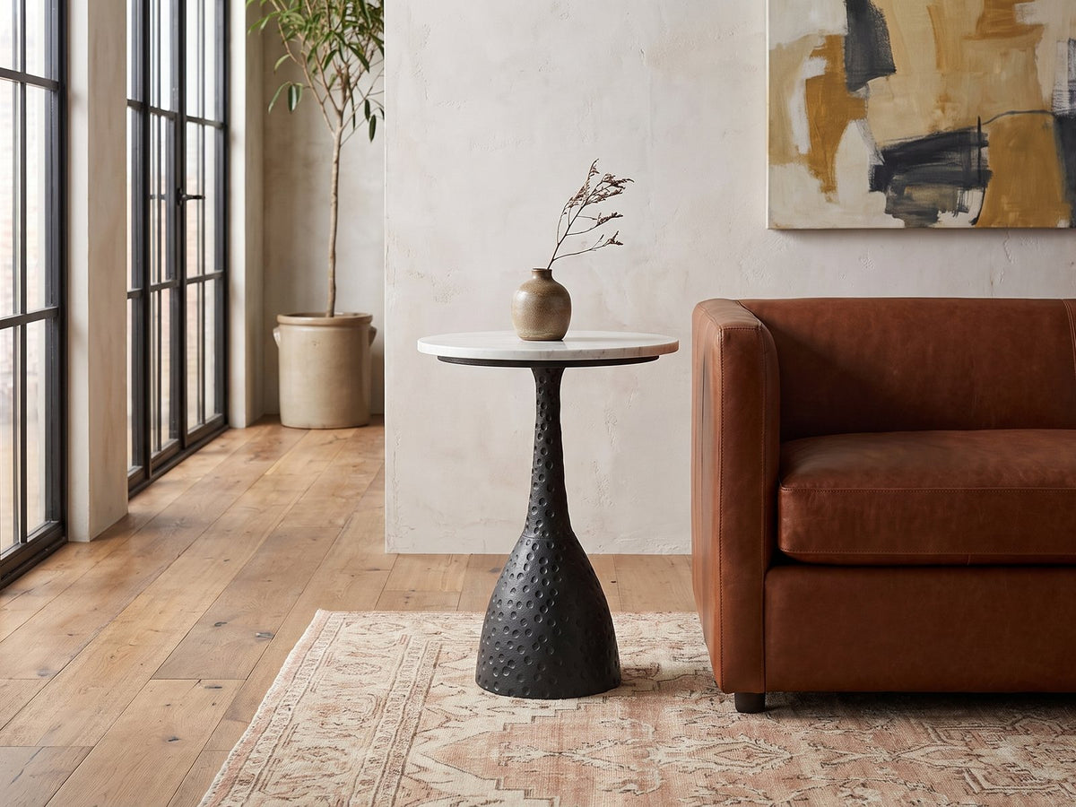 Orsara White Marble Pedestal Side Table beside a leather sofa in an industrial loft