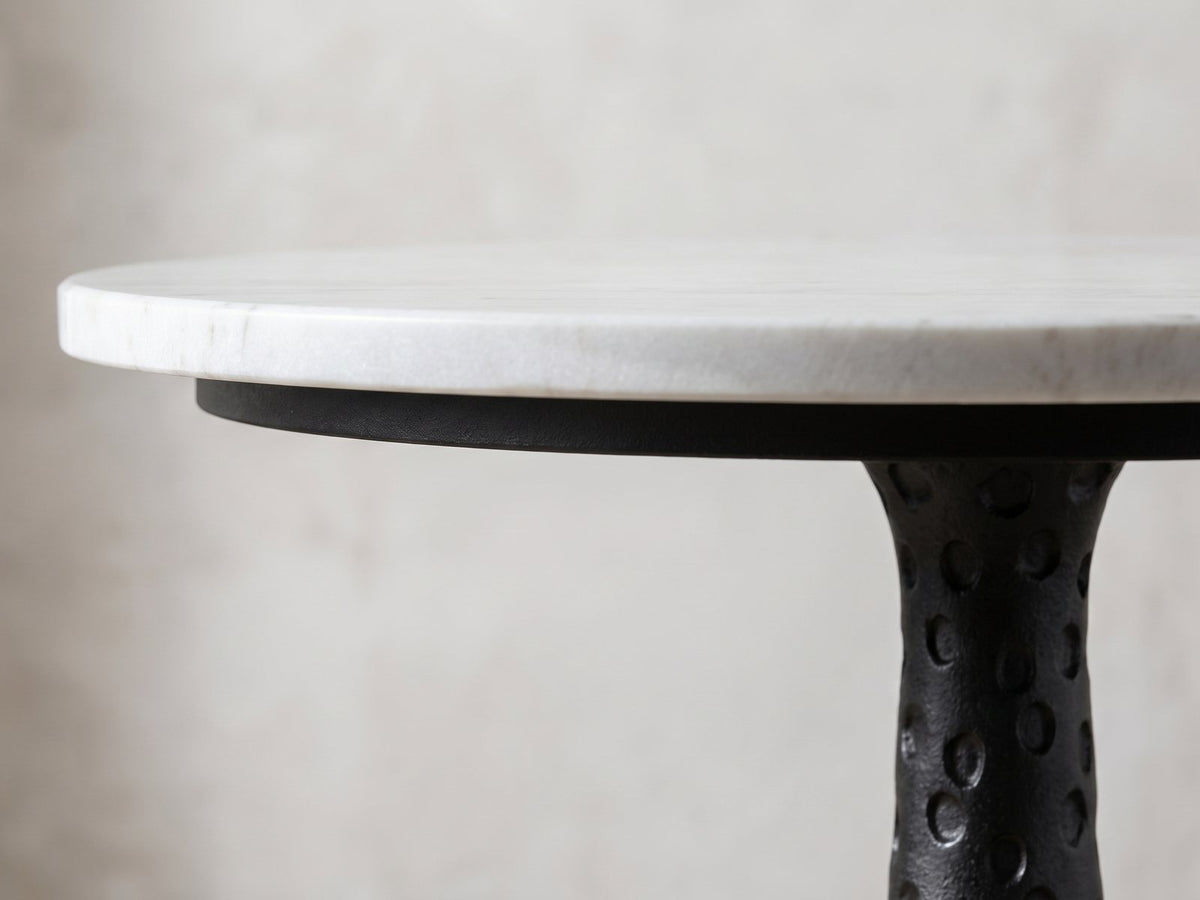 Close-up of the Orsara White Marble Pedestal Side Table: the white marble top edge over the hammered black base