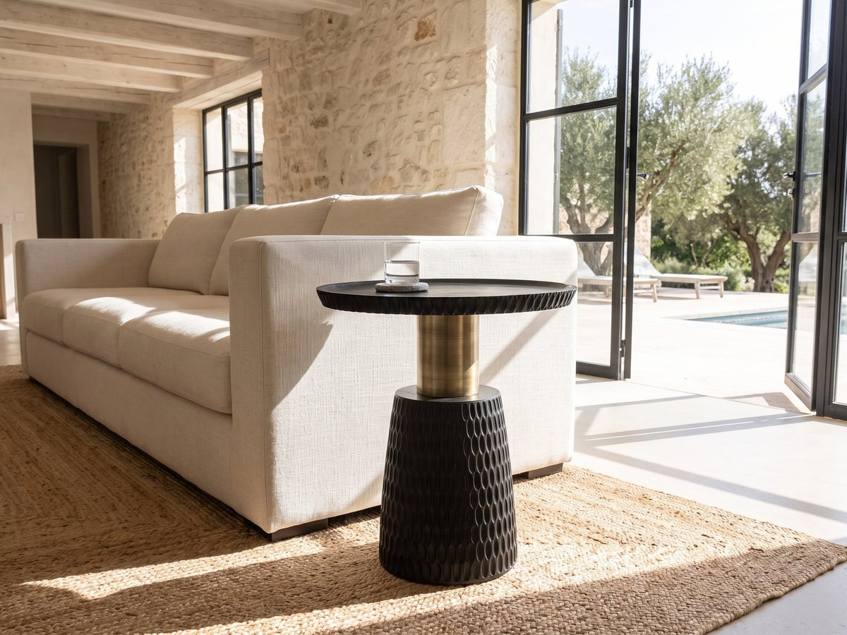 Orsomarso Carved Black Mango Pedestal Side Table beside a linen sofa in a poolside villa