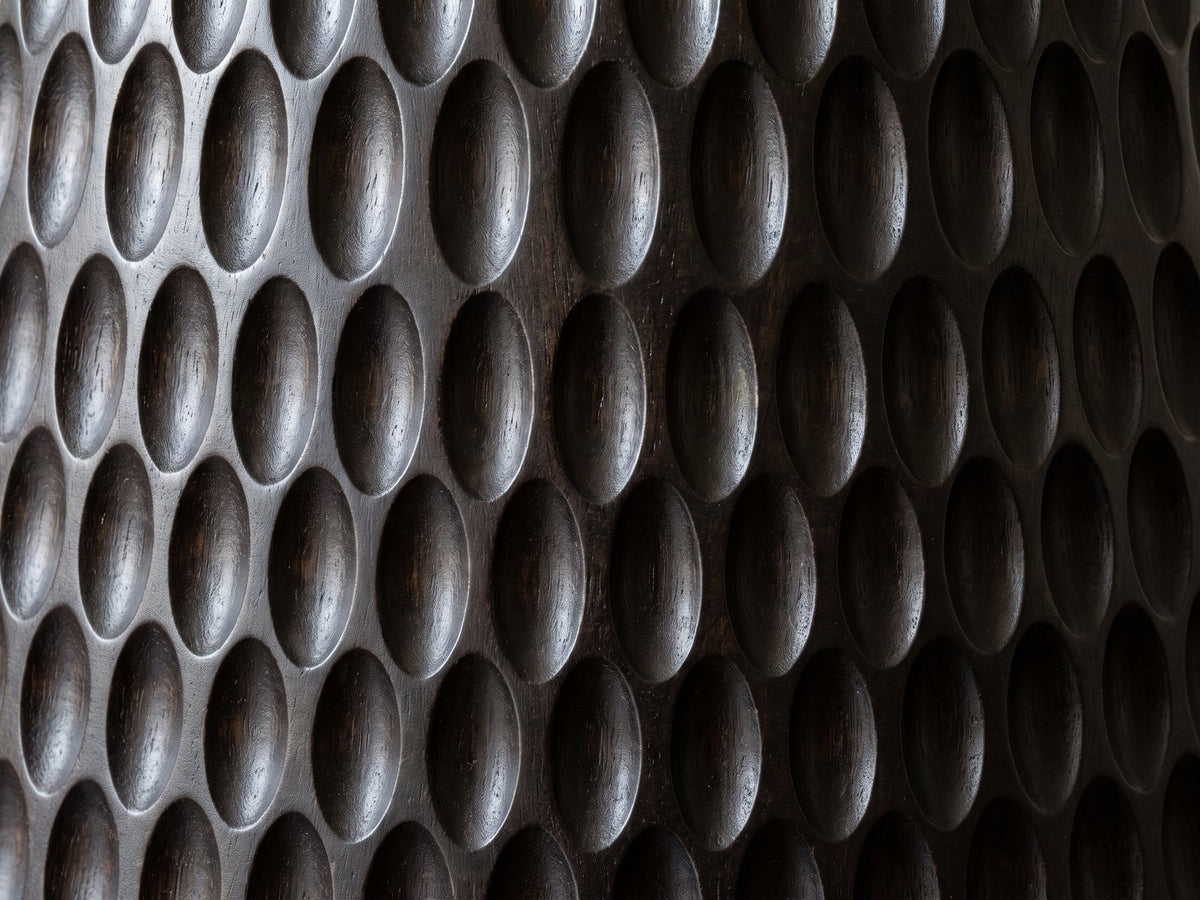 Close-up of the Orsomarso Carved Black Mango Pedestal Side Table: the hand-carved oval scoops of the black mango base