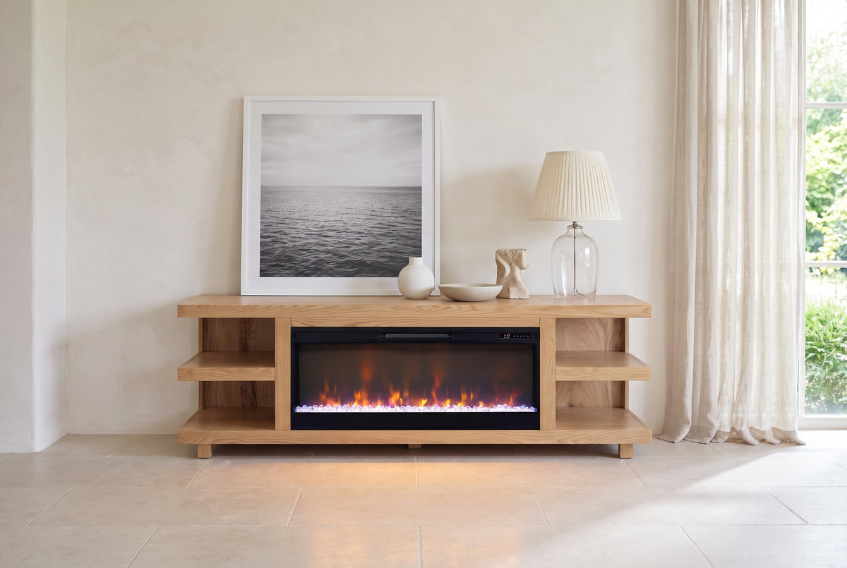 Ortisei Oak Fireplace Media Console styled with a leaning print, a lamp and ceramics in a bright plaster room, the fire lit