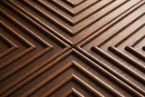 Close-up of the carved relief on the Ozieri nightstand door: raised rounded ash mouldings in nested right angles meeting in a cross, on a darker ground with open ash grain