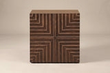 The Ozieri nightstand in walnut-brown ash, front view on a light studio backdrop: a plain top and one door carved in four mirrored quarters of nested right angles meeting in a cross