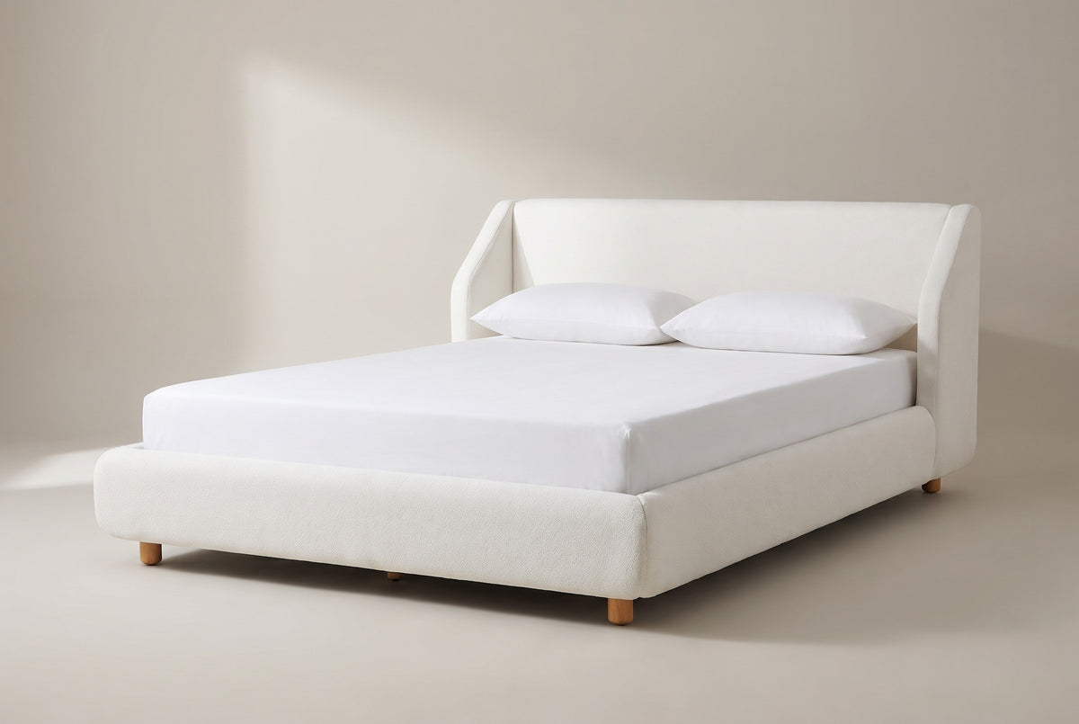The Pacentro bed in white boucle with a white mattress and pillows (not included), three-quarter view on a light studio backdrop