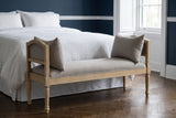 Paciano greige bench at the foot of a bed with white linen bedding in a Boston townhouse bedroom with a deep navy wall and a dark herringbone floor (bed not included)