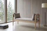 Paciano greige bench against a wall of pale cedar boards in a Seattle living room with a polished concrete floor, a floor-to-ceiling window onto fir trees and a floor lamp