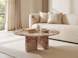 Paestum Rosa Marble Coffee Table styled with books, a vase and a stone bowl in front of a cream sofa in a bright plaster room