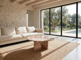 Paestum Rosa Marble Coffee Table on a jute rug in front of a linen sofa in a poolside villa