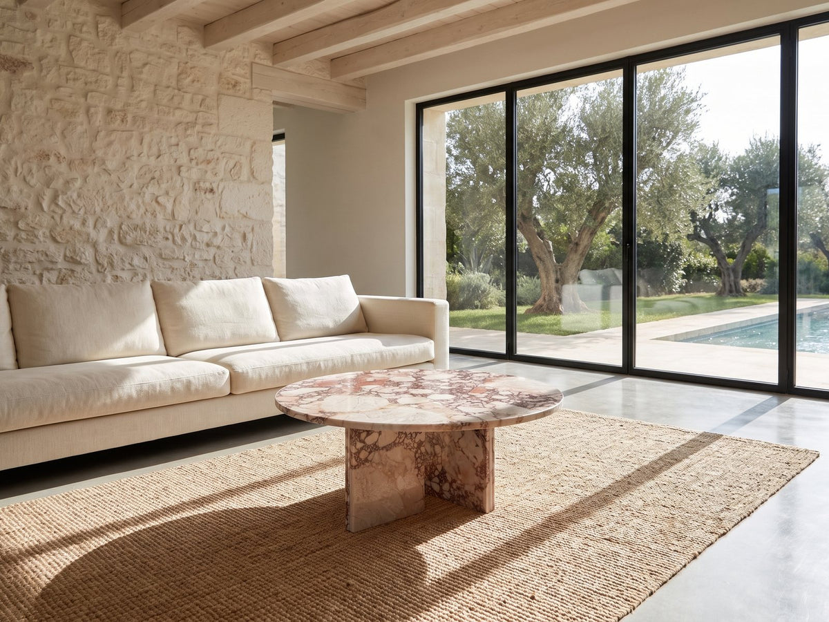 Paestum Rosa Marble Coffee Table on a jute rug in front of a linen sofa in a poolside villa
