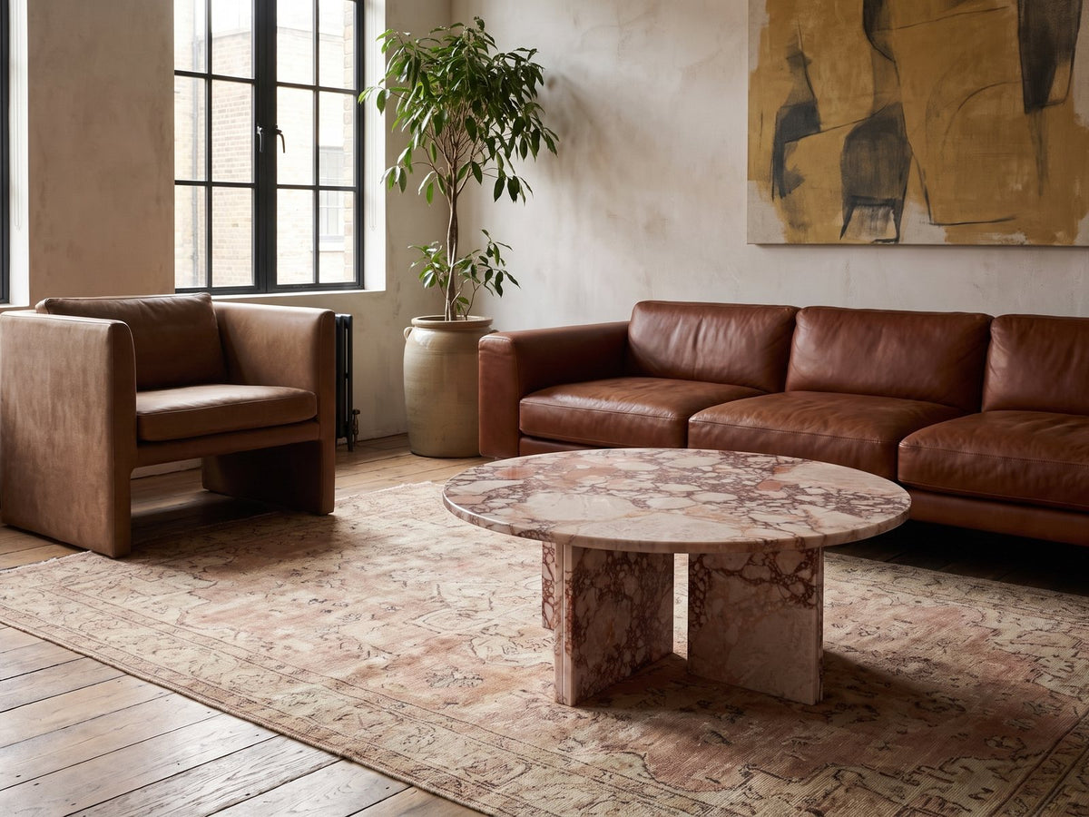 Paestum Rosa Marble Coffee Table on a vintage rug in front of a leather sofa in an industrial loft