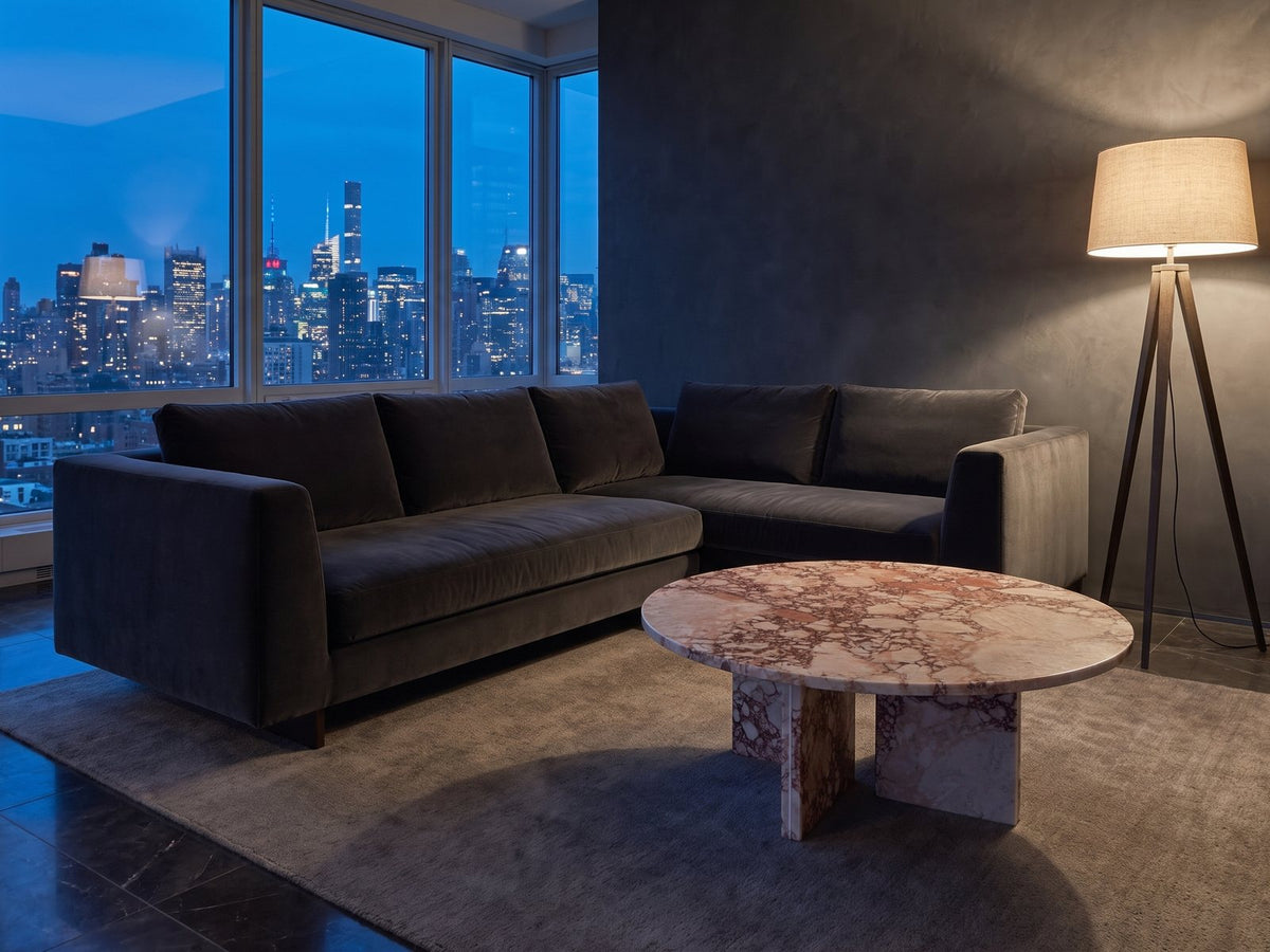 Paestum Rosa Marble Coffee Table on a wool rug in front of a velvet sofa in a city penthouse at blue hour