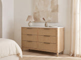 Palmanova 62-Inch Natural Wood and White Stone 6-Drawer Dresser against a plaster wall under an abstract canvas in a bright bedroom