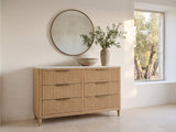 Palmanova 62-Inch Natural Wood and White Stone 6-Drawer Dresser under a round bronze mirror in a villa bedroom