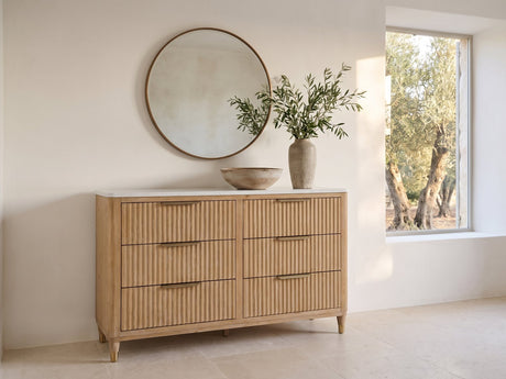 Palmanova 62-Inch Natural Wood and White Stone 6-Drawer Dresser under a round bronze mirror in a villa bedroom