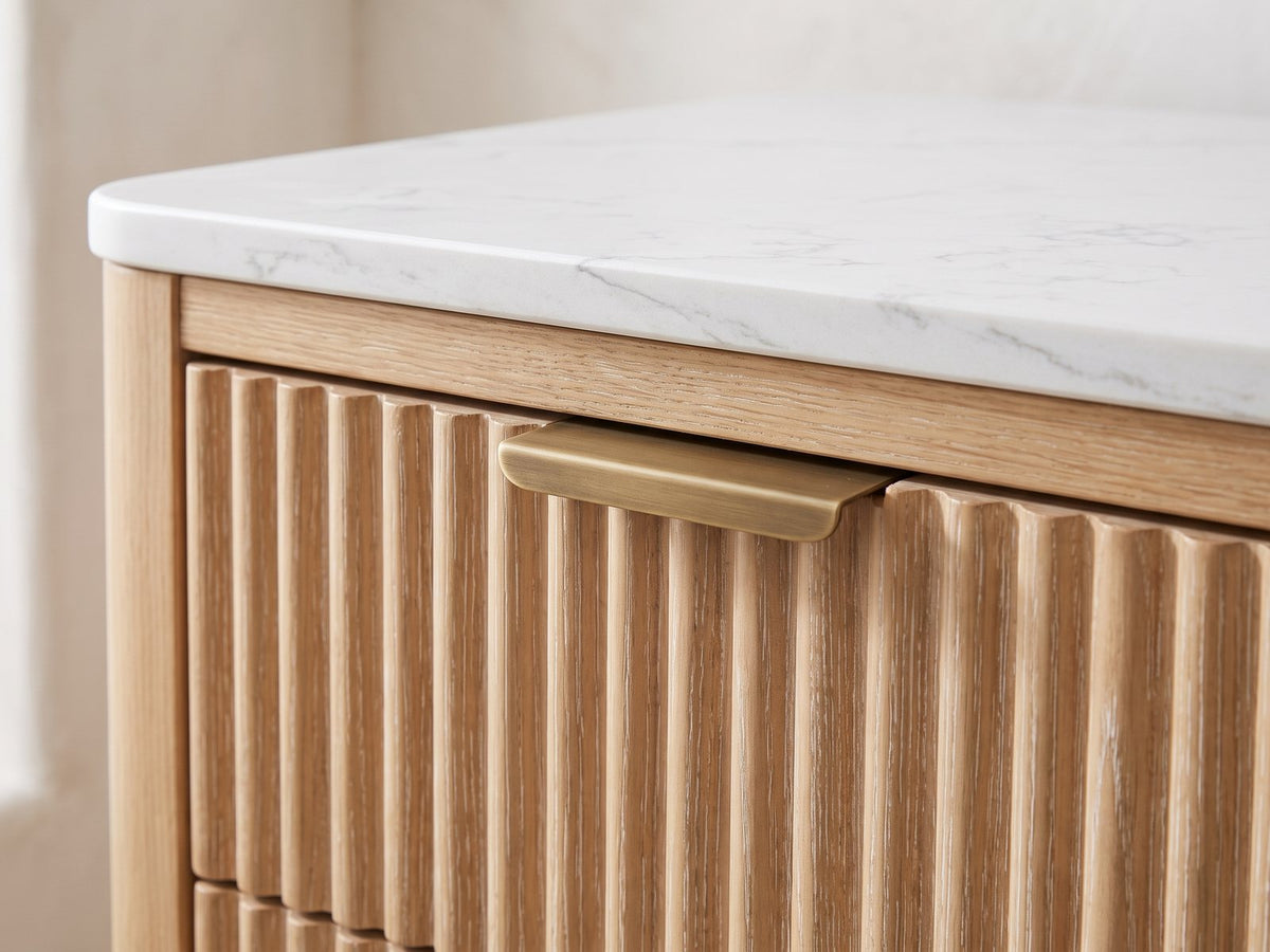 Close-up of the Palmanova 62-Inch Natural Wood and White Stone 6-Drawer Dresser: the brass edge pull on a reeded drawer front under the white stone top