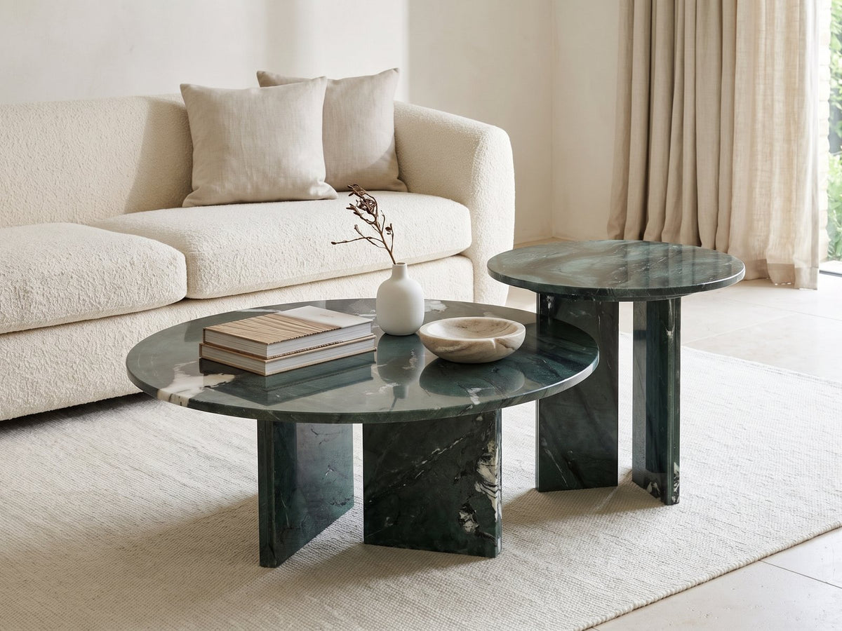 Panarea Verde Marble Nesting Coffee Tables, Set of 2 styled with books, a vase and a stone bowl in front of a cream sofa in a bright plaster room