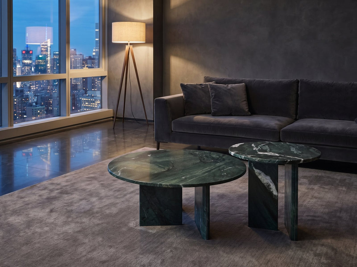 Panarea Verde Marble Nesting Coffee Tables, Set of 2 on a wool rug in front of a velvet sofa in a city penthouse at blue hour