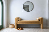 Panicale camel velvet bench against a pale limestone plaster wall in an Austin entry hall with a round black mirror, a terrazzo floor, a seagrass basket and a pair of loafers