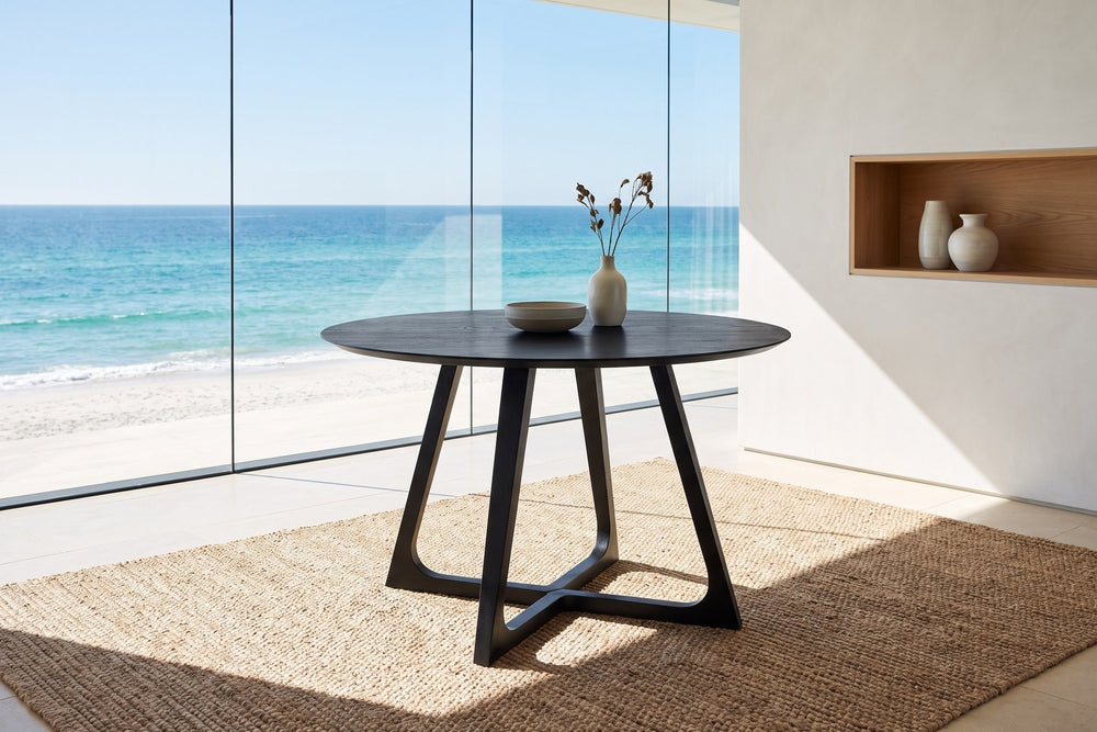 Paola 47.5-Inch Round Black Ash Dining Table in an oceanfront glass house
