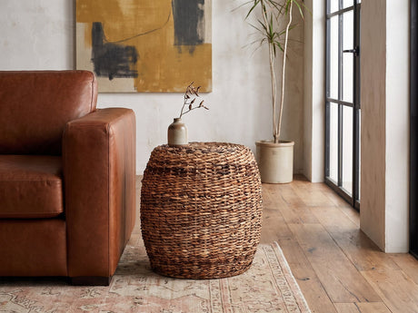 Parabita Woven Natural Fiber Barrel Side Table beside a leather sofa in an industrial loft