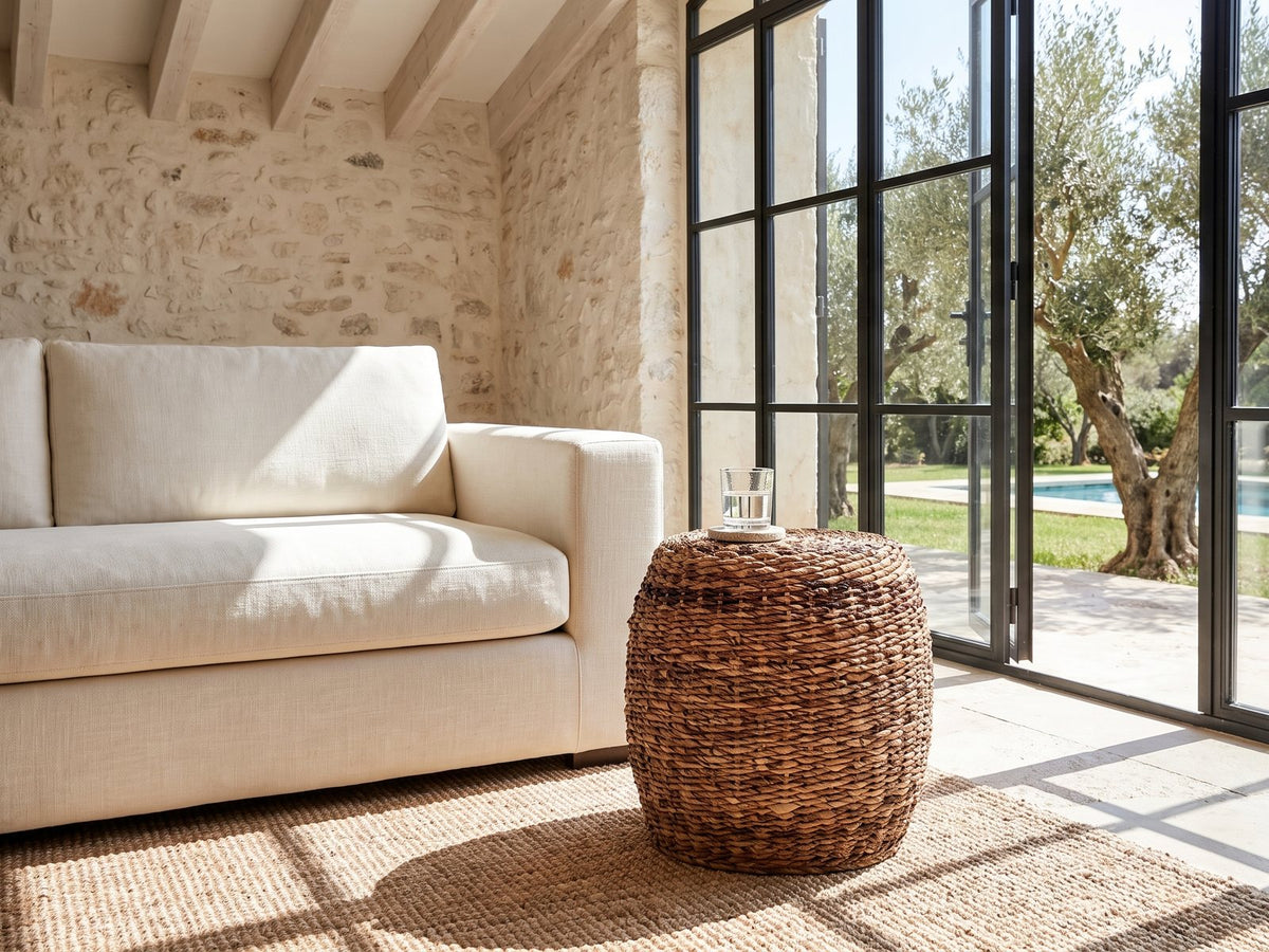 Parabita Woven Natural Fiber Barrel Side Table beside a linen sofa in a poolside villa