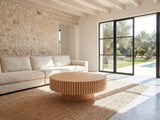 Pesaro Ash Veneer Fluted Pedestal Coffee Table on a jute rug in front of a linen sofa in a poolside villa