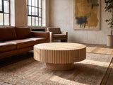 Pesaro Ash Veneer Fluted Pedestal Coffee Table on a vintage rug in front of a leather sofa in an industrial loft