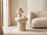 Pescocostanzo Cream Textured Fiberglass Mushroom Side Table with a lamp and a ceramic bowl beside a cream boucle sofa in a bright plaster room