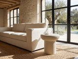 Pescocostanzo Cream Textured Fiberglass Mushroom Side Table beside a linen sofa in a poolside villa