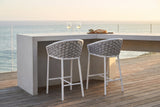Two Petralia counter stools with grey rope backs at a pale concrete counter on a teak-decked ocean-view terrace in Laguna Beach at golden hour (counter not included)