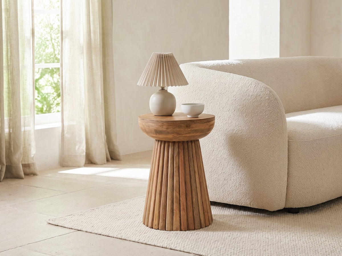 Petroio Fluted Mango Mushroom Side Table with a lamp and a ceramic bowl beside a cream boucle sofa in a bright plaster room