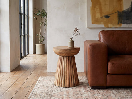 Petroio Fluted Mango Mushroom Side Table beside a leather sofa in an industrial loft
