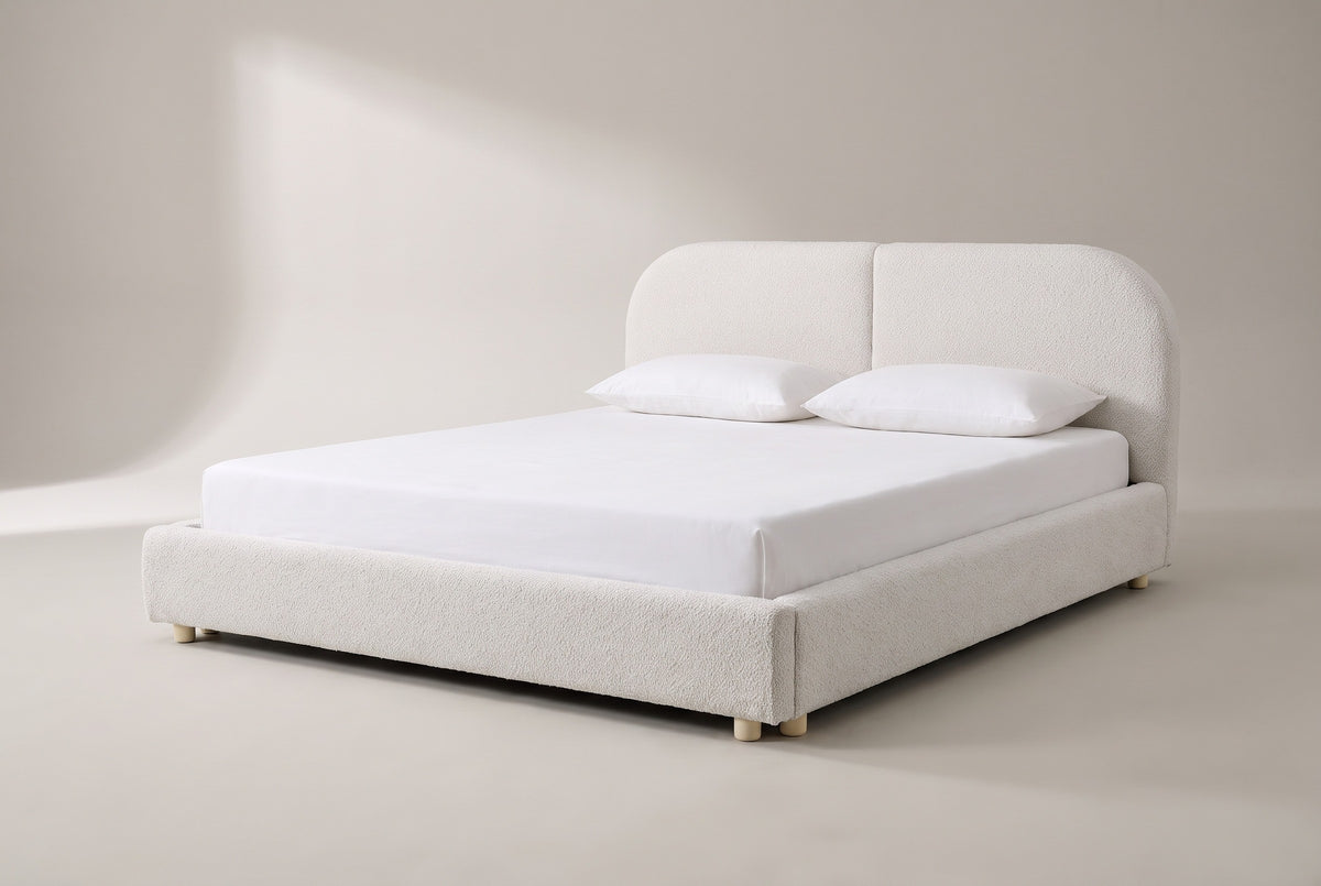 The Pietrabbondante bed in ivory boucle with a white mattress and pillows (not included), three-quarter view on a light studio backdrop