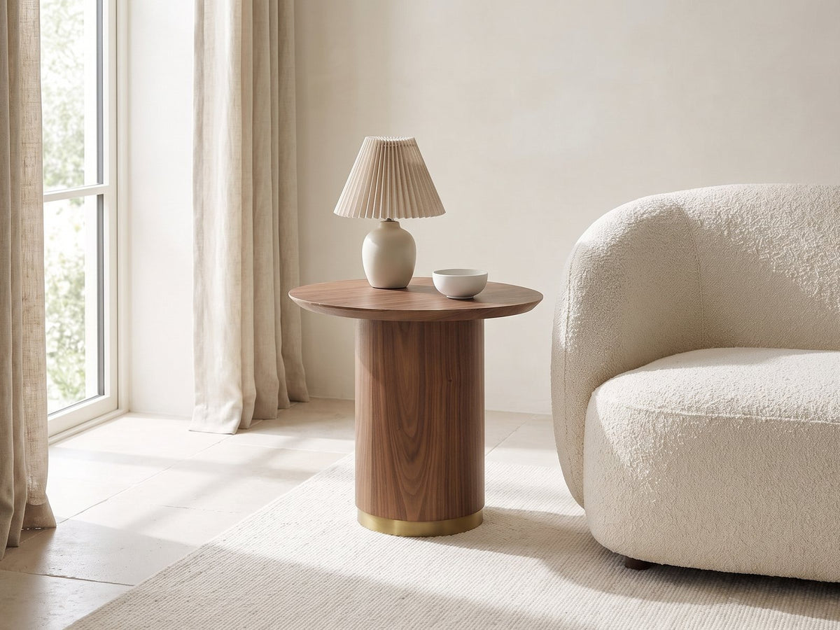 Pietrapertosa Walnut Pedestal Side Table with a lamp and a ceramic bowl beside a cream boucle armchair in a bright plaster room