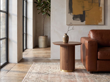 Pietrapertosa Walnut Pedestal Side Table beside a cognac leather armchair in an industrial loft