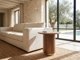 Pietrapertosa Walnut Pedestal Side Table beside a linen sofa in a poolside villa