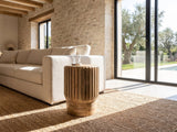 Pievepelago Natural Mango Fluted Drum Side Table beside a linen sofa in a poolside villa